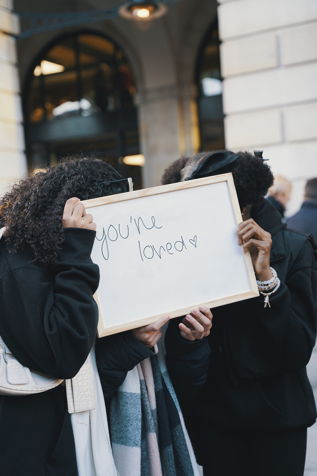 Two young people holding a sign saying 'You're loved'.