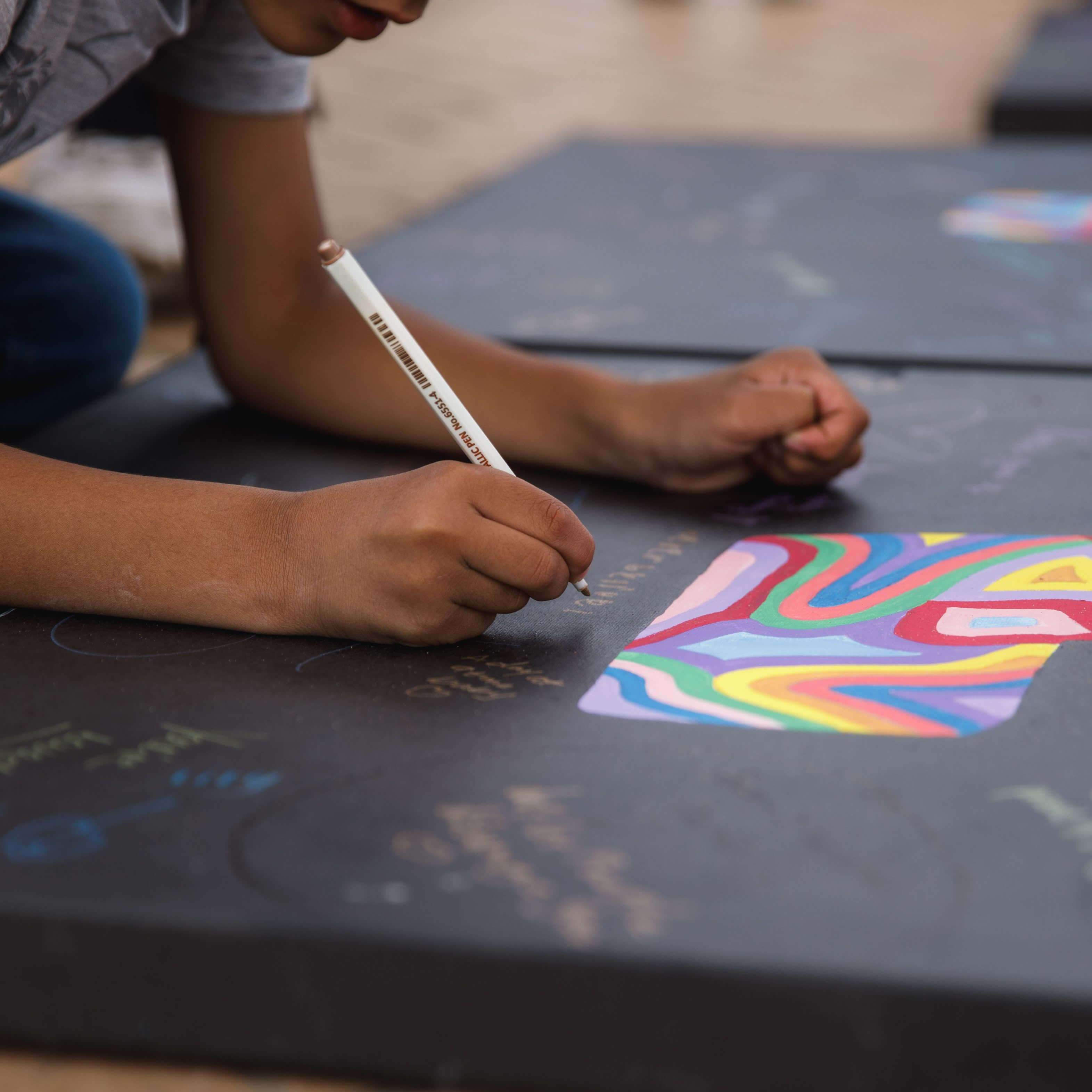 Child writing on a canvas at the Messages of Hope 2023 event