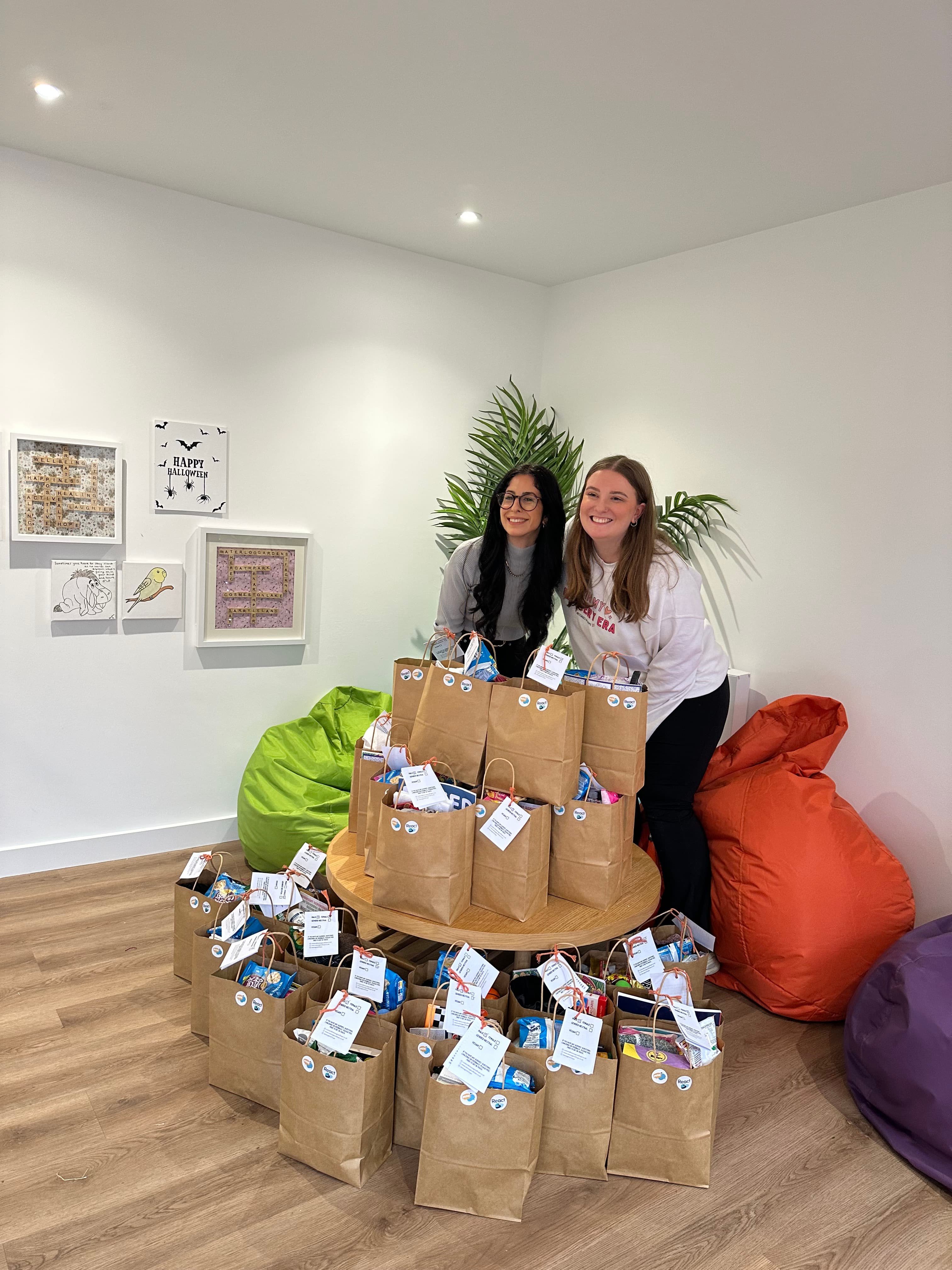 Bethan and Emmanuella standing behind a collection of Bags of Hope ready to be delivered